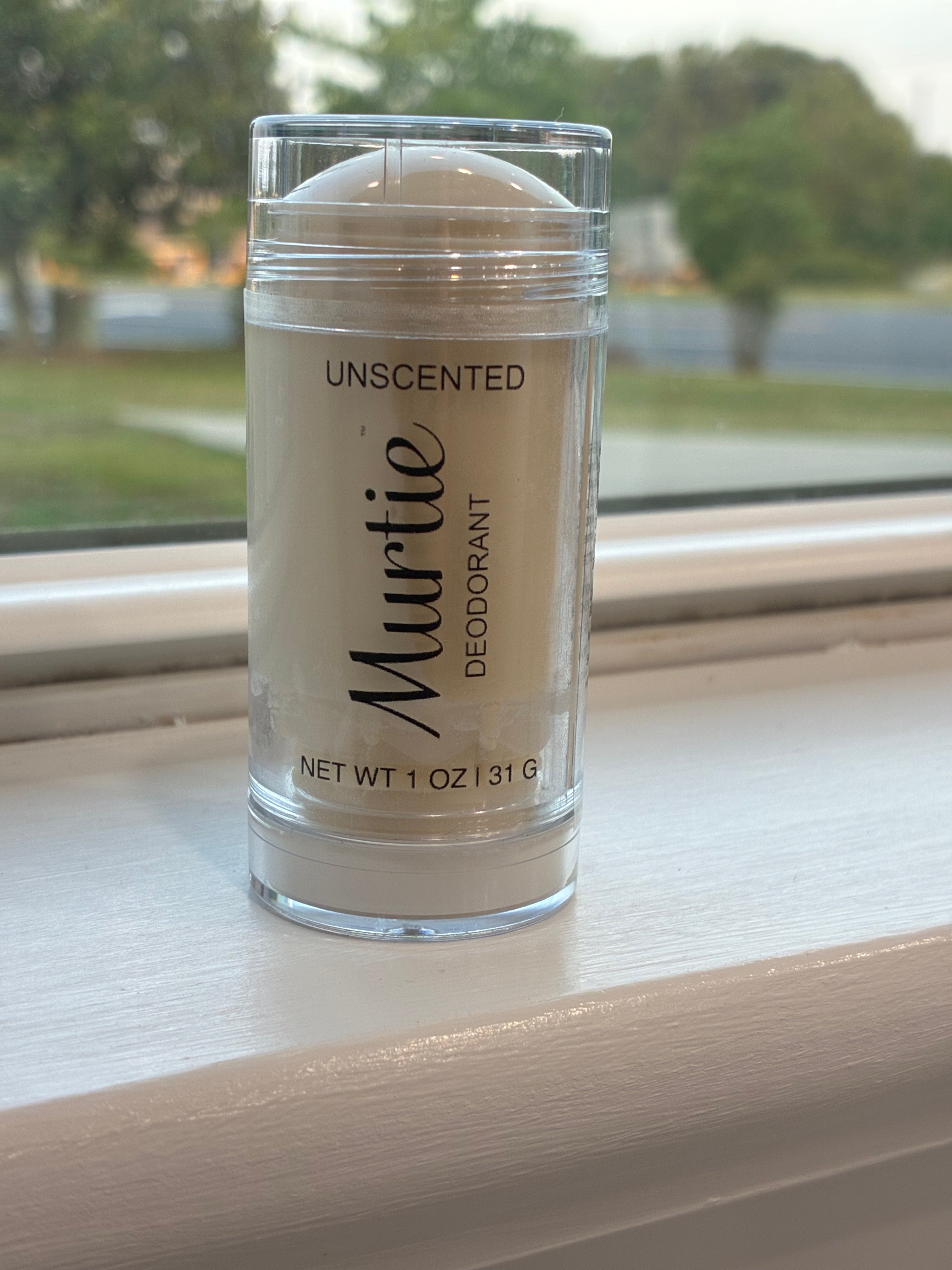 Murtie deodorant stick on a windowsill with a blurred outdoor background